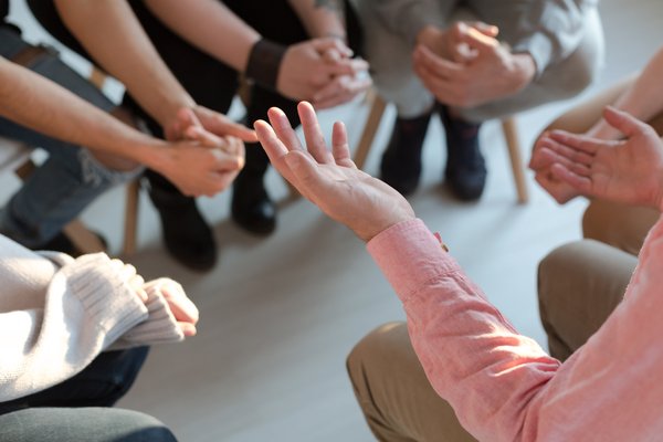 Hände von im Kreis sitzenden Personen