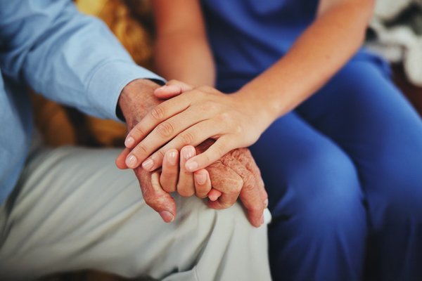 Hand einer jungen Person liegt auf der Hand einer alten Person